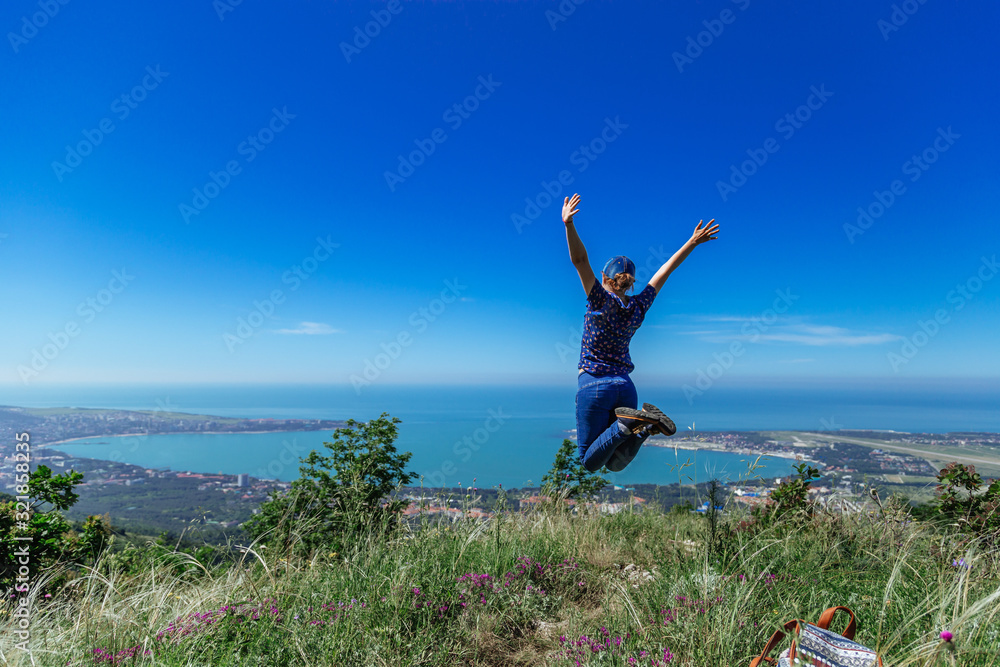 Girl jumps on the slope of a ridge.  Late spring (early summer) Gelendzhik.