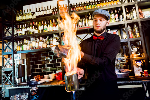 The bartender makes a cocktail with a fire show at the bar