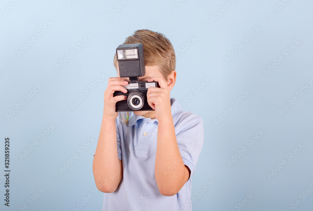 a child with a retro camera on a blue background, a creative smart blond boy in a blue Polo shirt a child with a retro camera on a blue background, a creative smart blond boy in a blue Polo shirt
