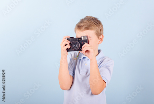 a child with a retro camera on a blue background, a creative smart blond boy in a blue Polo shirt