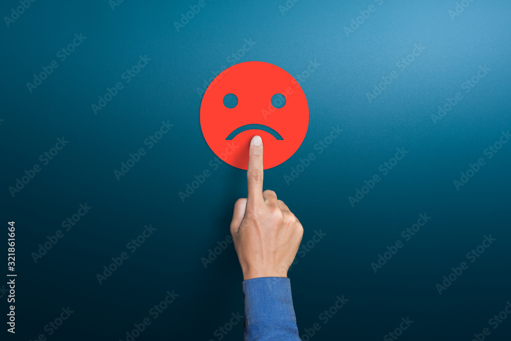 The client's hand choose the red sad face icon, Customer service evaluation, dissatisfaction in service concepts, copy space - obrazy, fototapety, plakaty 