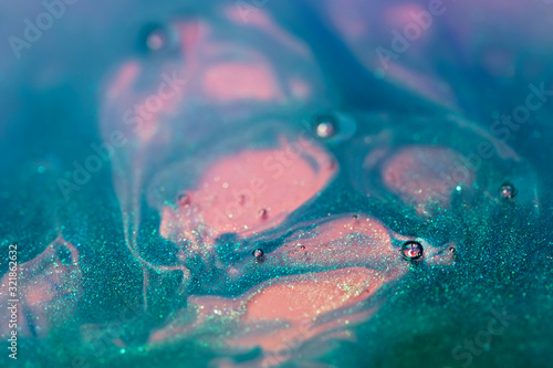 turquoise and pink alcohol ink with glitter dissolved in water, abstract background, macro view