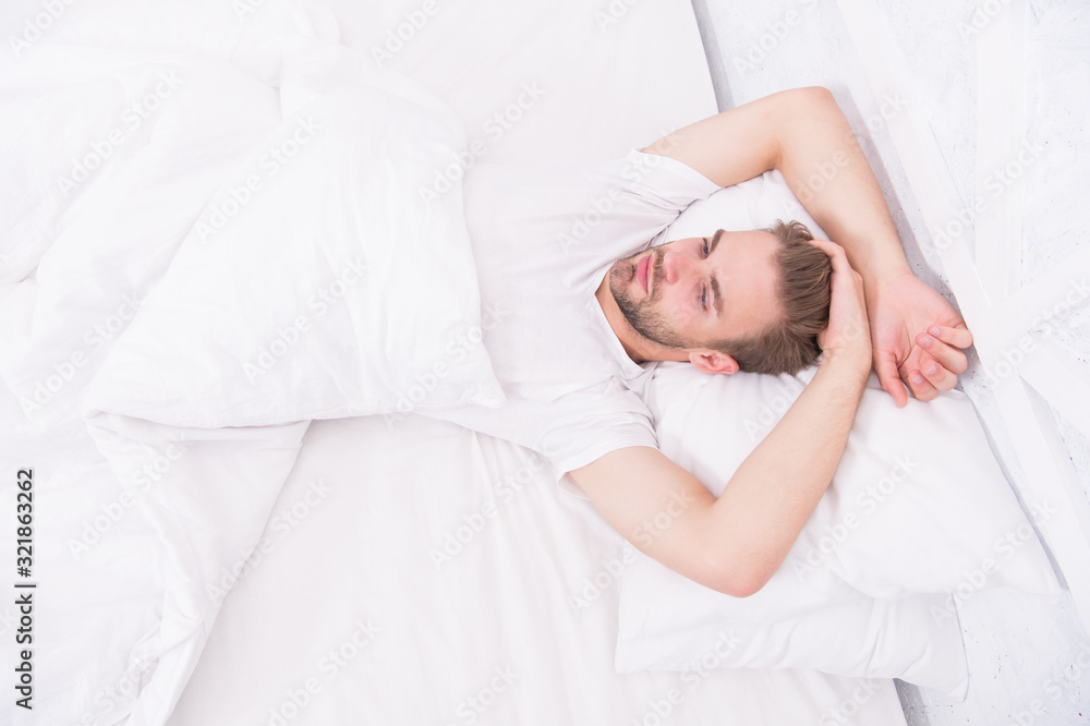 Tips promoting healthful sleep habits. Handsome man relaxing in bed. Establish regular nightly sleep pattern. Practice calming activities such as meditation before going to bed. Healthy sleep concept Tips promoting healthful sleep habits. Handsome man relaxing in bed. Establish regular nightly sleep pattern. Practice calming activities such as meditation before going to bed. Healthy sleep concept