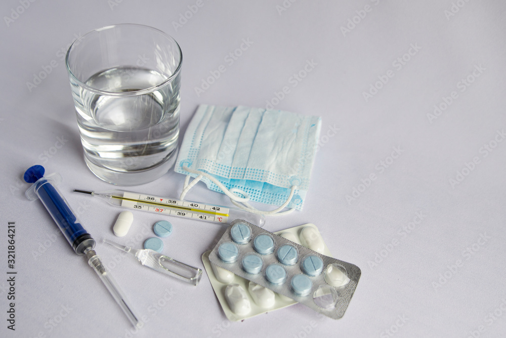 A glass of water, a thermometer with a high temperature indicator, a medical mask, tablets. White background, no one A glass of water, a thermometer with a high temperature indicator, a medical mask, tablets. White background, no one