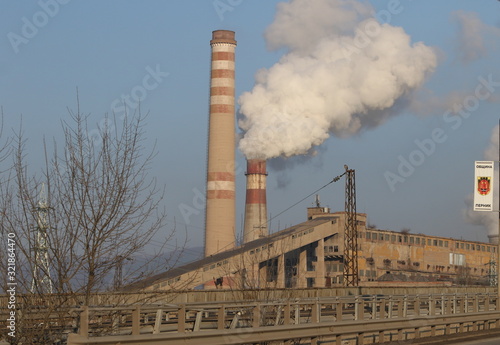 Old smoking chimney of thermal power station plant background of blue