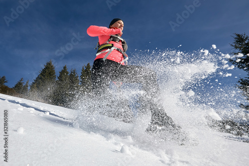 Trail runner woman running in winter mountains on snow. Dynamic running downhill on trail woman athlete runner side view