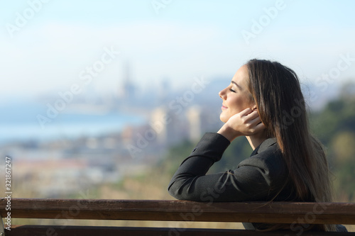 Businesswoman relaxing on a bench with eyes closed photo