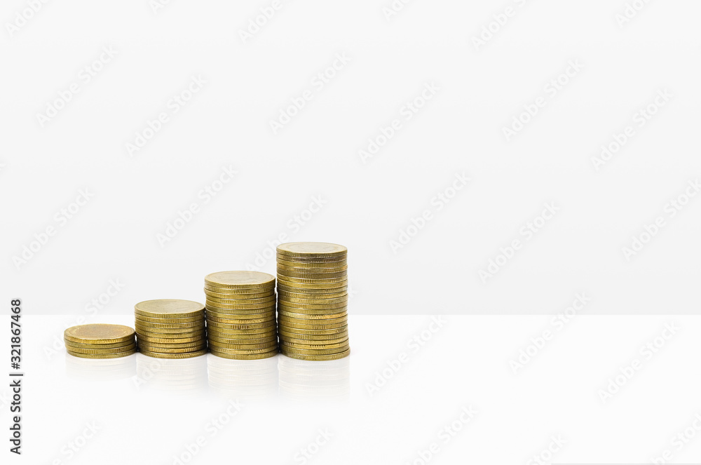 Growing stacked of coins on white table and background with space for text. Business and finance concept. Growing stacked of coins on white table and background with space for text. Business and finance concept.