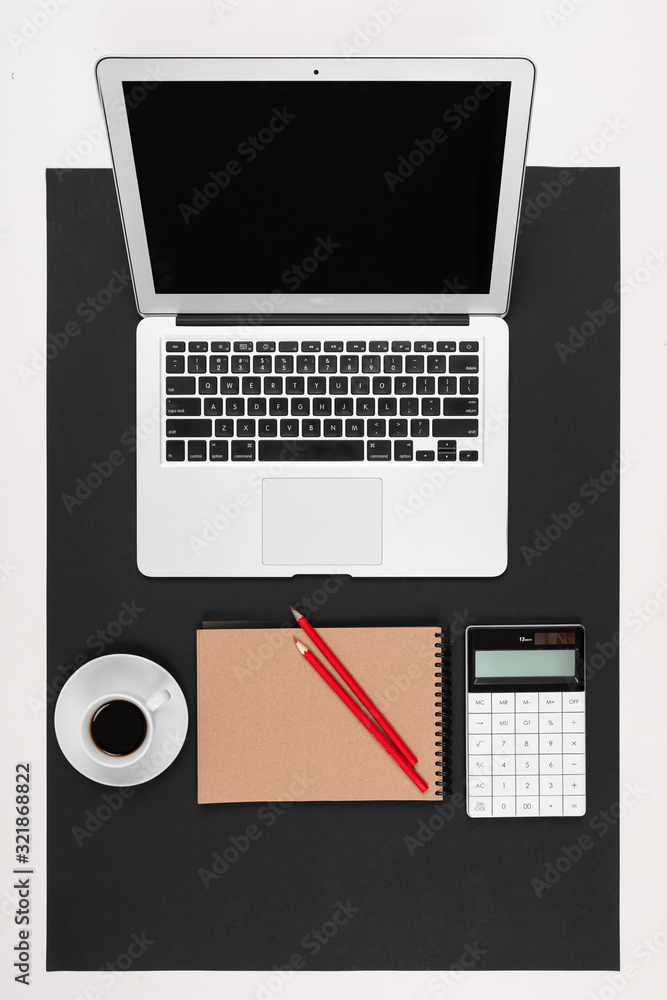 Desktop with laptop, note, pen, calculator, cup of coffee isolated on black and white background Desktop with laptop, note, pen, calculator, cup of coffee isolated on black and white background