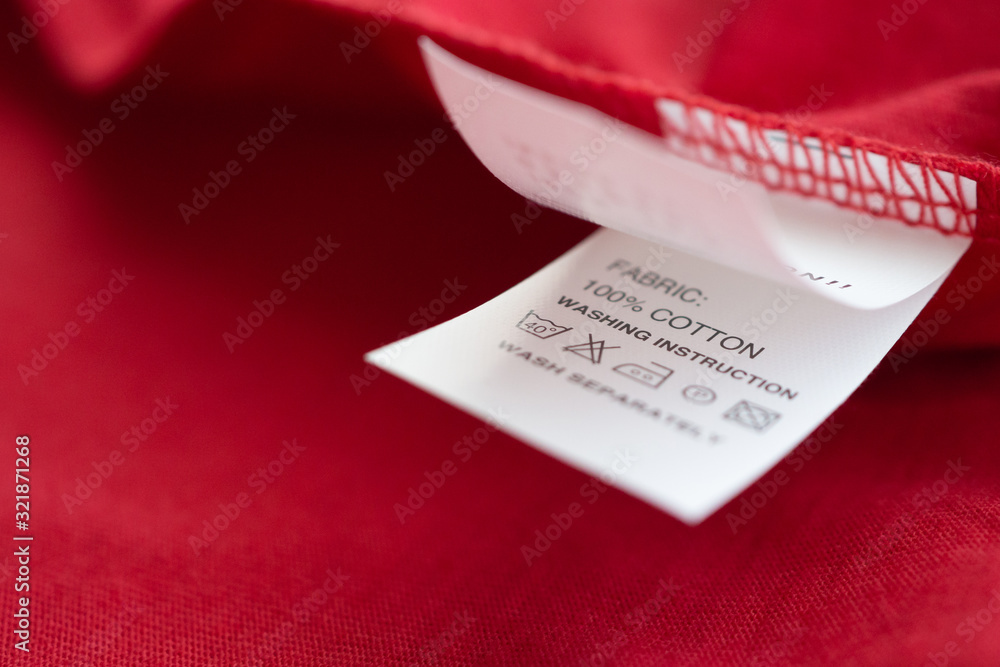 Fototapeta premium White laundry care washing instructions clothes label on red cotton shirt