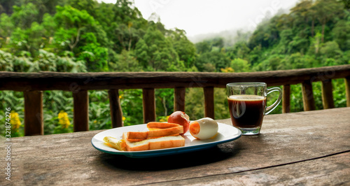 Breakfast and blackcoffee at balcony with forest and mountain scenery in morning, Chiangmai, Thailand