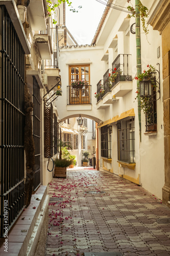 Fototapeta Naklejka Na Ścianę i Meble -  Marbella, Spain - August 26th, 2018. Typical old town street with Spanish architecture in Marbella, Costa del Sol, Andalusia, Spain, Europe