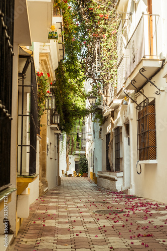 Fototapeta Naklejka Na Ścianę i Meble -  Marbella, Spain - August 26th, 2018. Typical old town street with Spanish architecture in Marbella, Costa del Sol, Andalusia, Spain, Europe