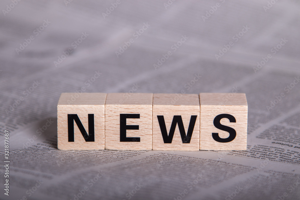news, text on wooden cubes, newspaper as background