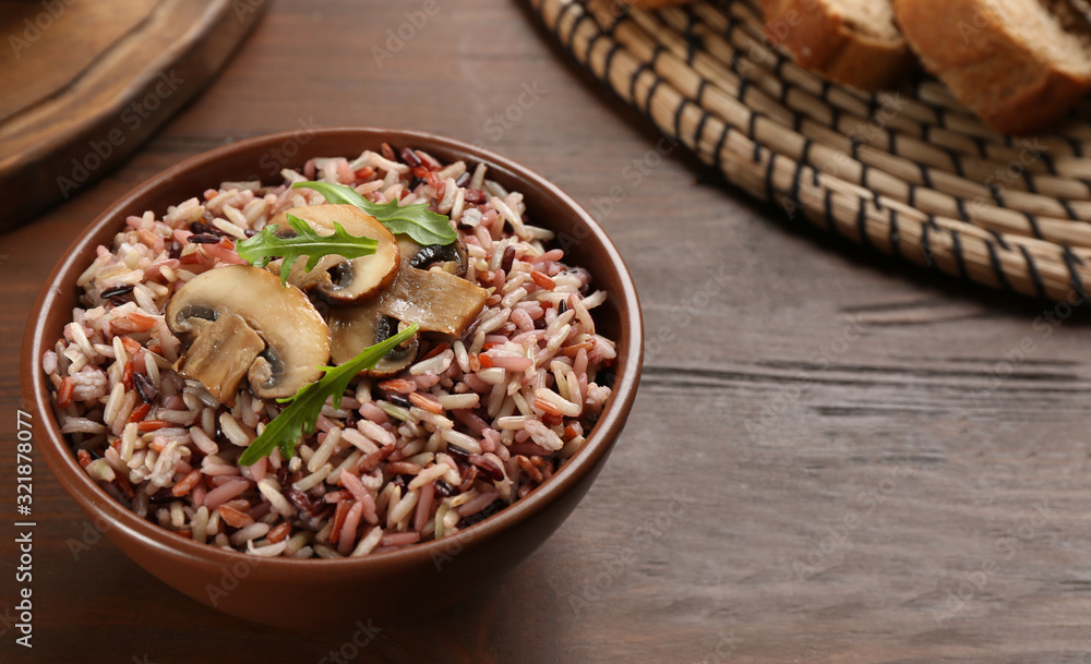 Fototapeta premium Delicious brown rice in bowl on wooden table
