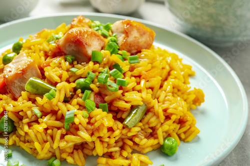 Delicious rice pilaf with vegetables and chicken on plate, closeup