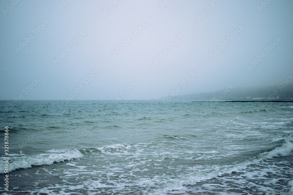 Fototapeta premium Seascape with city view in cold misty weather