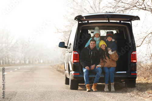 Happy family with little children in modern car trunk on road
