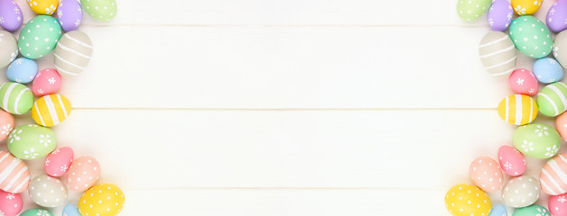 Pastel colored Easter Egg banner with double side border against a white wood background. Top view with copy space.