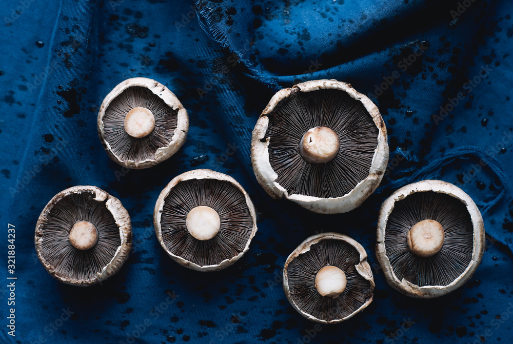 Overripe raw champignon mushrooms on a blue cloth healthy vegan food 