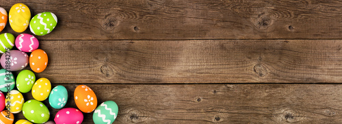 Colorful Easter Egg banner with corner border against a rustic old wood background. Top view with copy space.