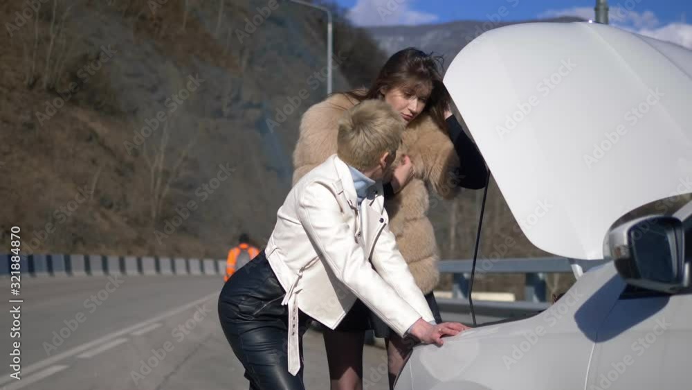 woman repairing the car. A man walks by, ignoring them. humor. woman repairing the car. A man walks by, ignoring them. humor.