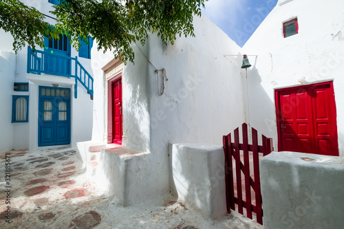 Amazing narrow streets of popular destination on Milos island. Greece. Traditional architecture and colors of mediterranean city. Colorful doors, white buildings and flowers at sunny paradise