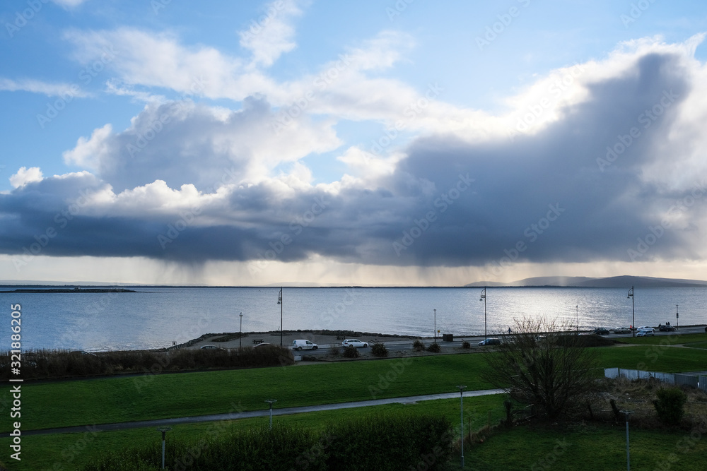 Rain clouds pouring over the ocean with blue sky. Taken on Salthill promenade in Galway, Ireland