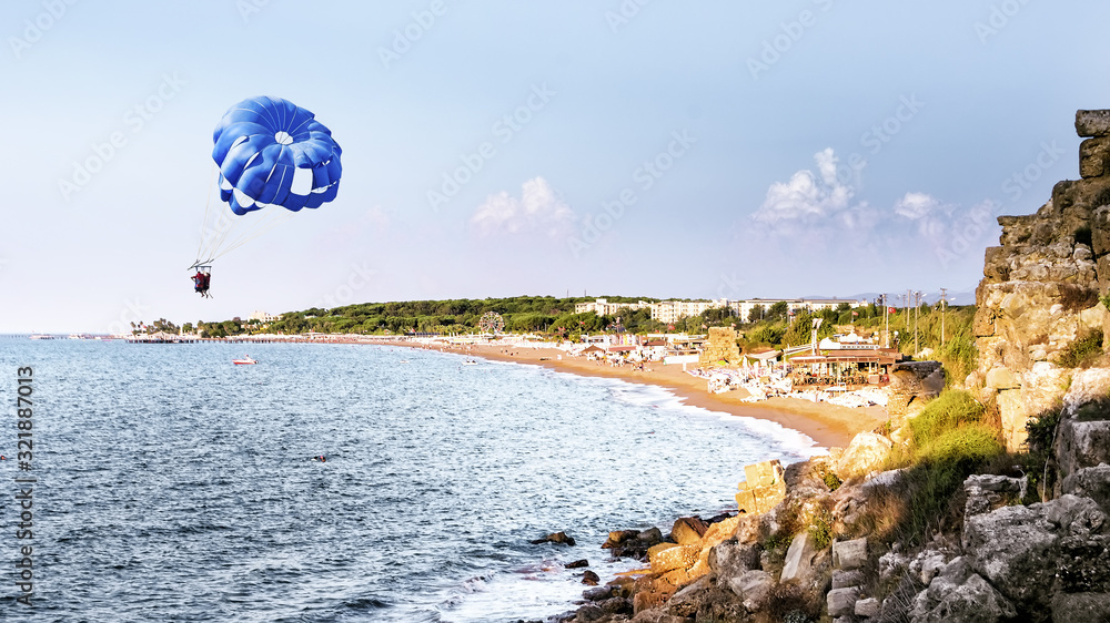Naklejka premium Two people parasailing on a blue parachute over the coast of Side, Turkey