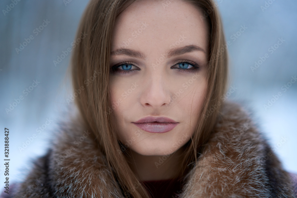Winter facial portrait of a beautiful Russian girl with blue eyes and a serious look dressed in a fur coat. Winter facial portrait of a beautiful Russian girl with blue eyes and a serious look dressed in a fur coat.