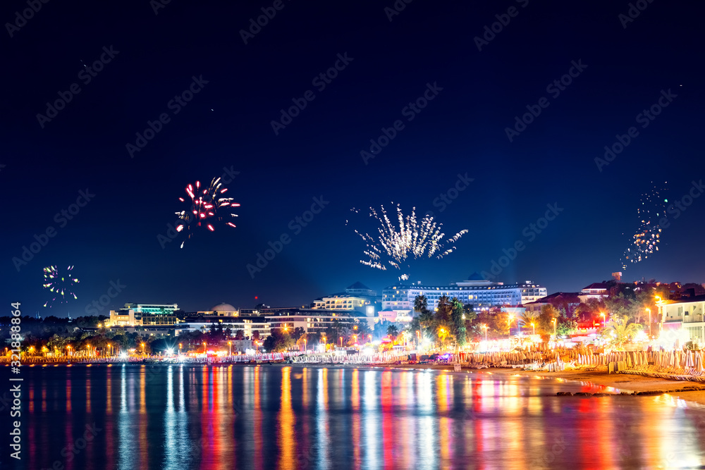 Festive fireworks and beautiful starlight of a night city, view of Side city at night. Nightly reflections of light on the beach of the Mediterranean Sea. turkey
