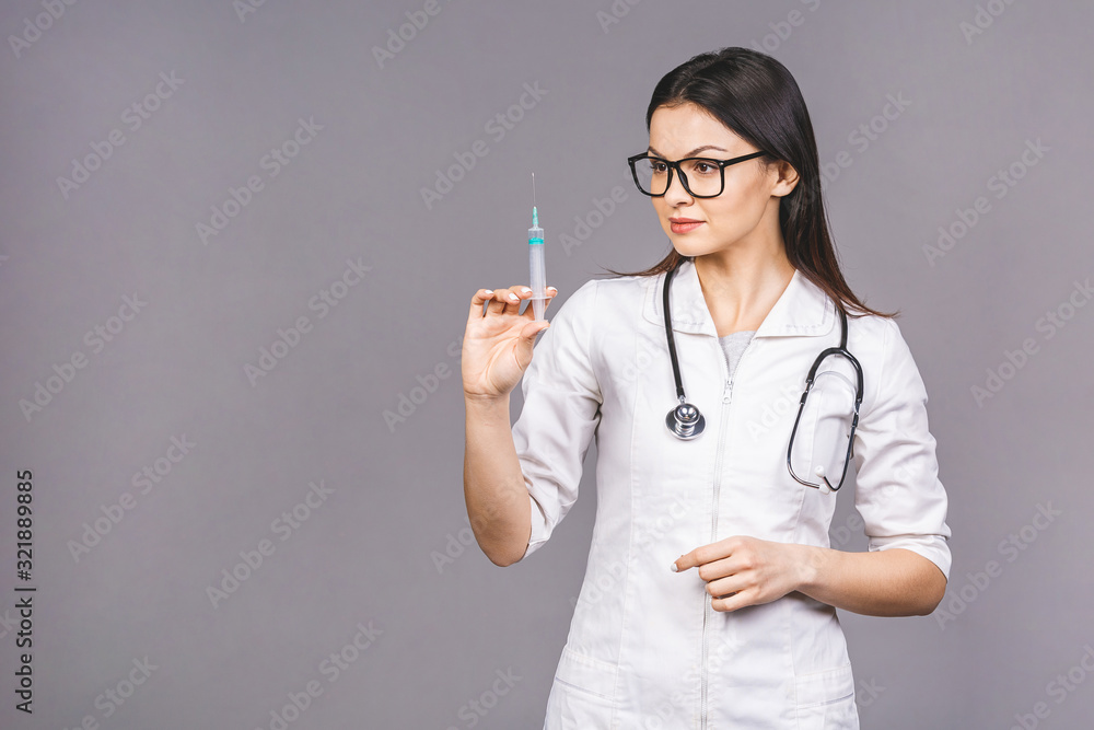 Portrait of serious female doctor in medical mask holding syringe for injection isolated on grey background. Portrait of serious female doctor in medical mask holding syringe for injection isolated on grey background.