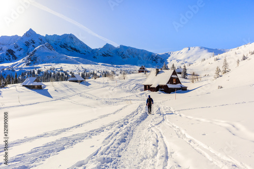Tourist backpacker walking in beautiful Gasienicowa valley in winter time, Tatra Mountains, Poland