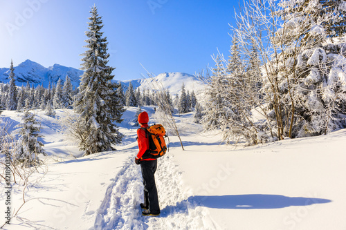 Young woman backpacker on walking trail in Gasienicowa valley during winter time, Tatra Mountains, Poland