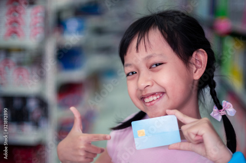 Smile child girl standing in super market with credit card