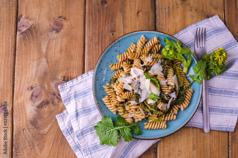 Cime di rapa pasta in a plate on with parmesan on a wooden table. Traditional food of the south of Italy, from Puglia. Rustic style photo. Copy space Cime di rapa pasta in a plate on with parmesan on a wooden table. Traditional food of the south of Italy, from Puglia. Rustic style photo. Copy space