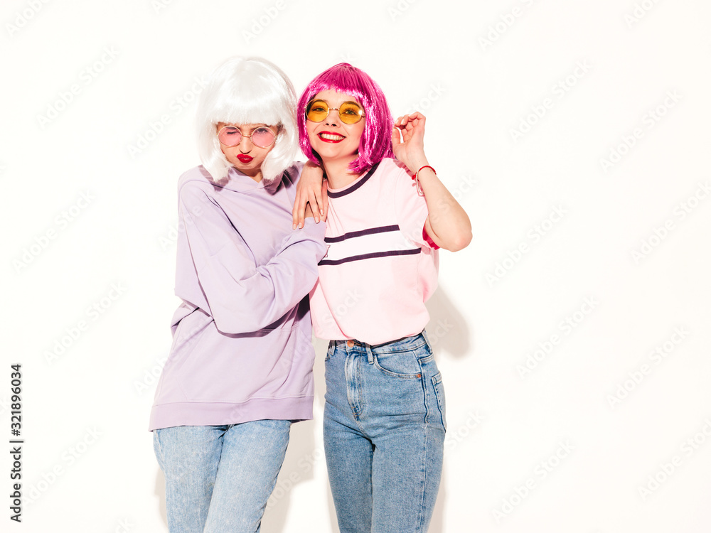 Two young sexy smiling hipster girls in wigs and red lips.Beautiful trendy women in summer clothes.Carefree models posing near white wall in studio.Positive female going crazy and hugging Two young sexy smiling hipster girls in wigs and red lips.Beautiful trendy women in summer clothes.Carefree models posing near white wall in studio.Positive female going crazy and hugging
