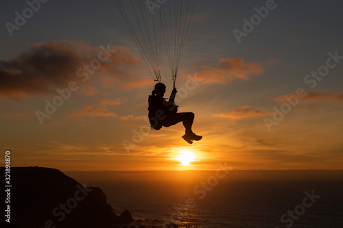 Paraglider flying over thesea shore at sunset. Paragliding sport concept.
