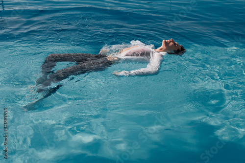  A man in a shirt swims in the pool