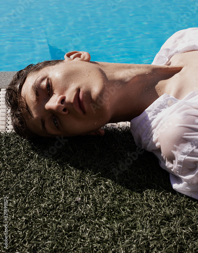  A man lies on a lawn by the pool