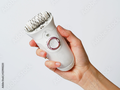 Female epilator white in a female hand on a white background. Electric hair removal device. Concept of skin care and female beauty. Women's suffering. photo