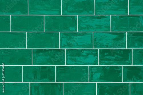 Seamless old and crooked shiny green ceramic tiled background texture.