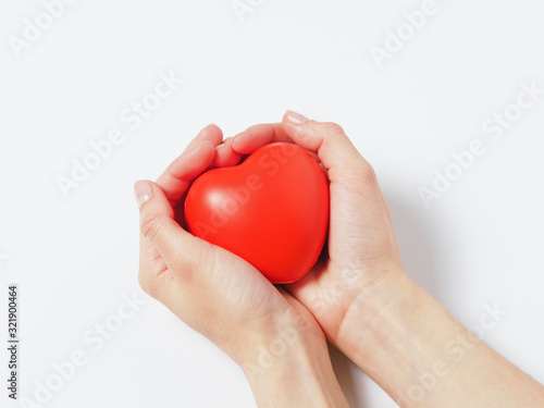 red heart in women's hands isolated on a white background. Concept of charity, health, and love