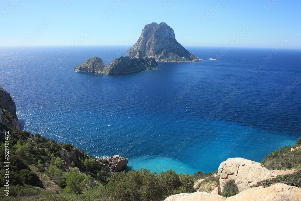 The magical island of Es Vedra with the small islet of Es Vedranell next to it in front of the coast of Cala d'Hort in the tourist island of Ibiza in the midst of nature between cliffs,