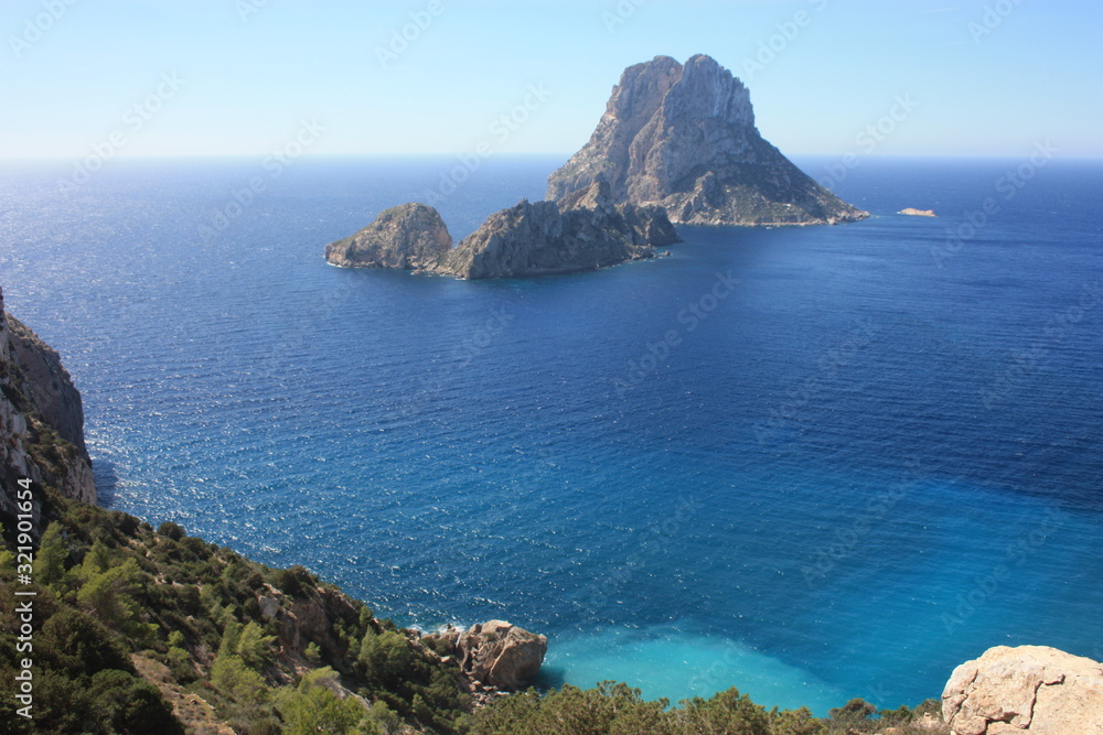 The magical island of Es Vedra with the small islet of Es Vedranell next to it in front of the coast of Cala d'Hort in the tourist island of Ibiza in the midst of nature between cliffs,