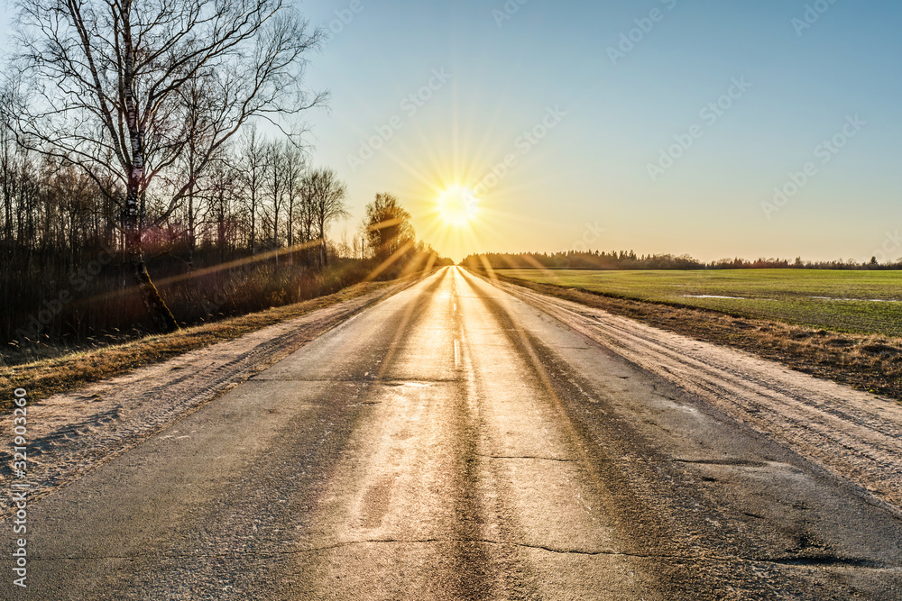 old asphalt road lit by the rays of the setting sun