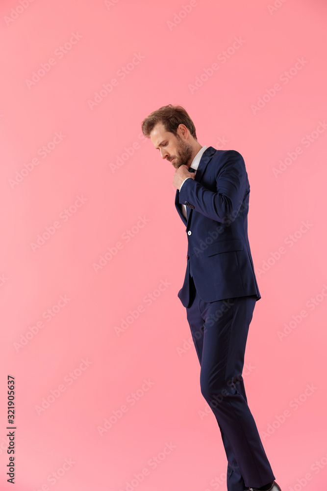 Side view of pensive businessman adjusting his tie Side view of pensive businessman adjusting his tie