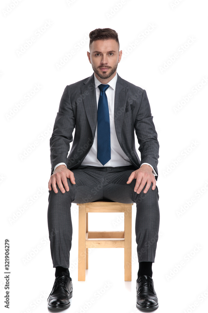 serious young businessman holding hands on knees serious young businessman holding hands on knees