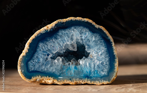 Geode with transparent crystals of light-blue color on a dark background..