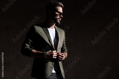 confident cool guy adjusting coat in a fashion light